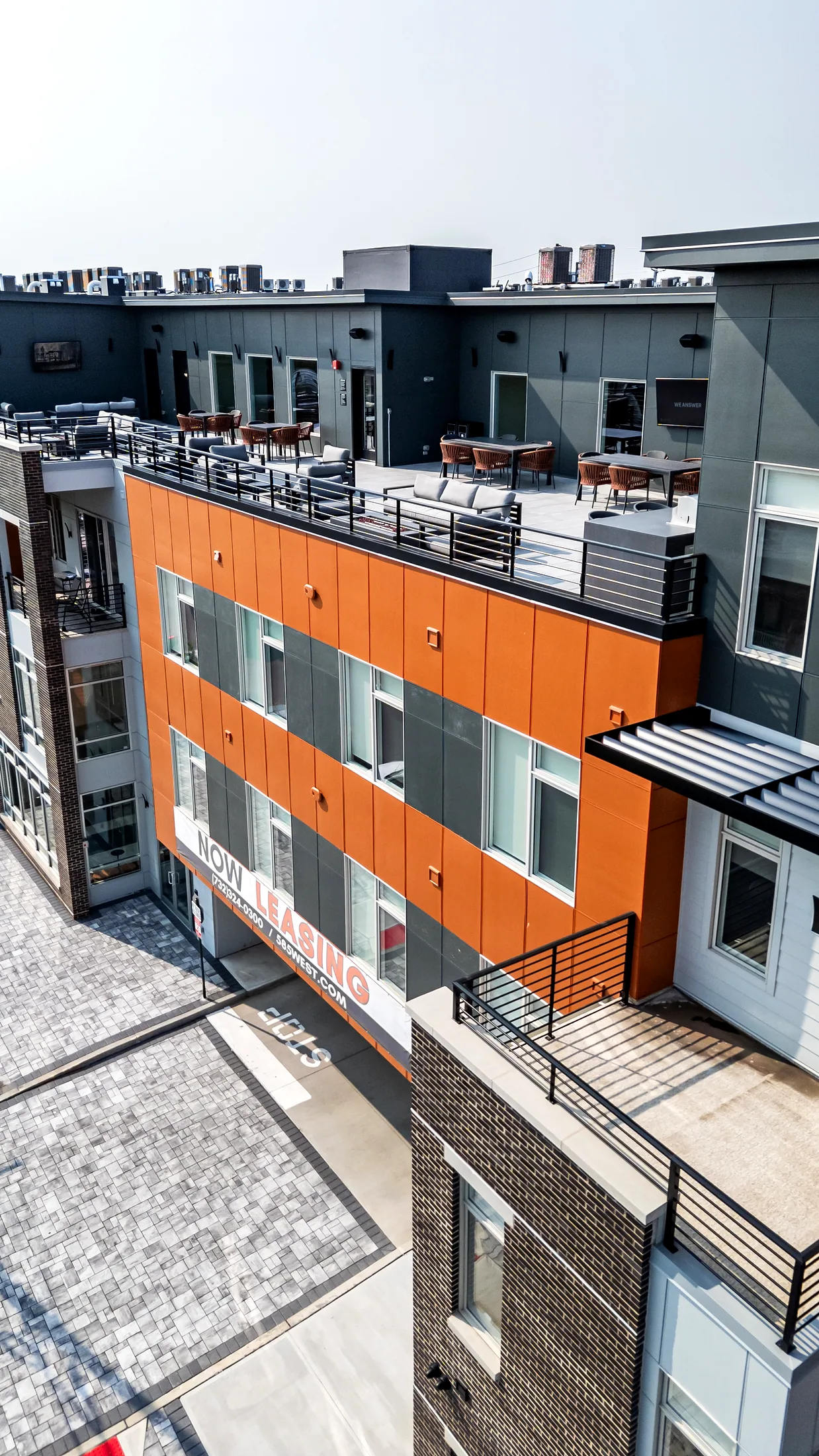 Corner of Five85West with orange cladding and the roof terrace railing above