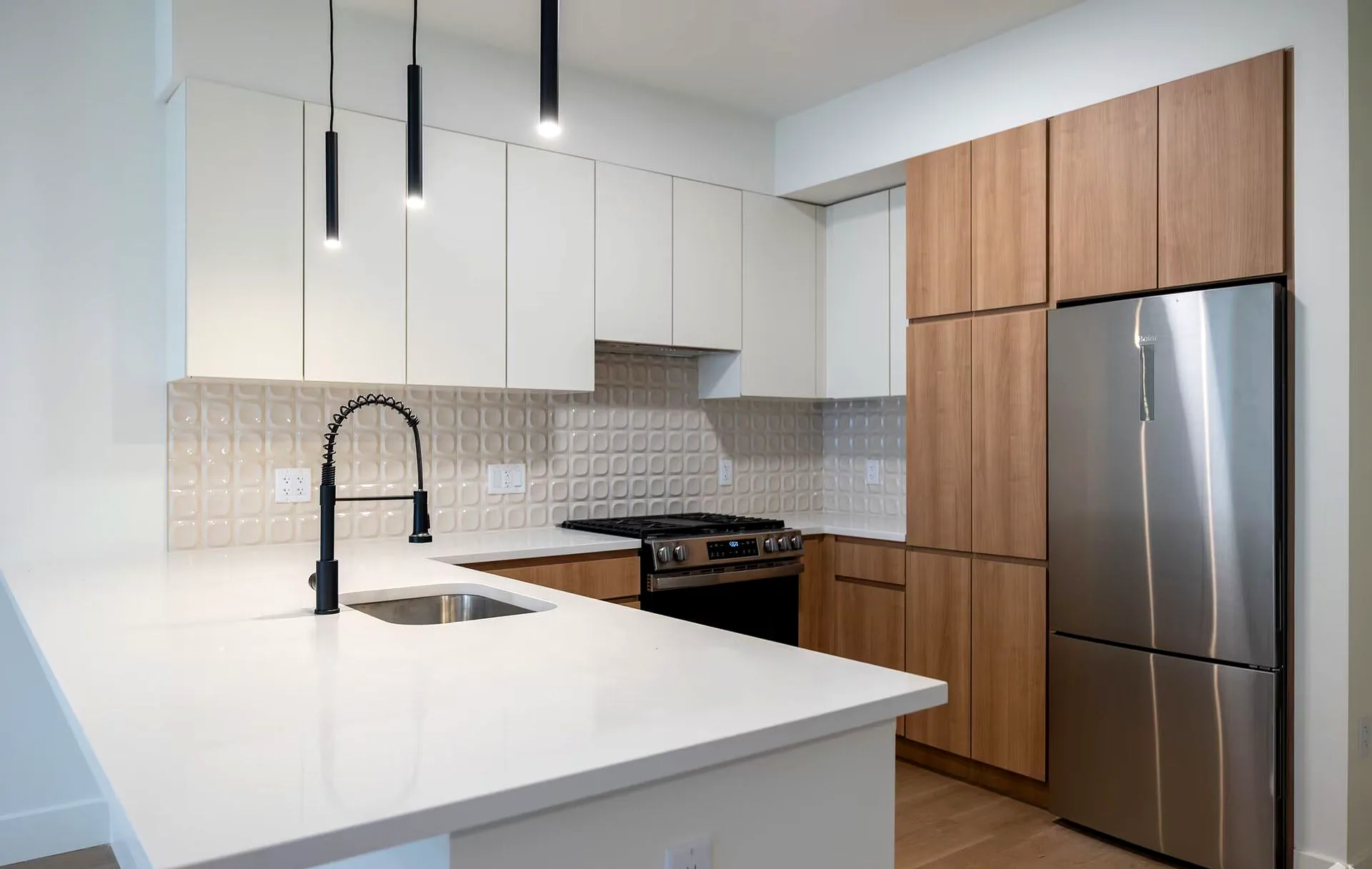 Kitchen with white quartz countertops, warm wood cabinetry, and matte black fixtures