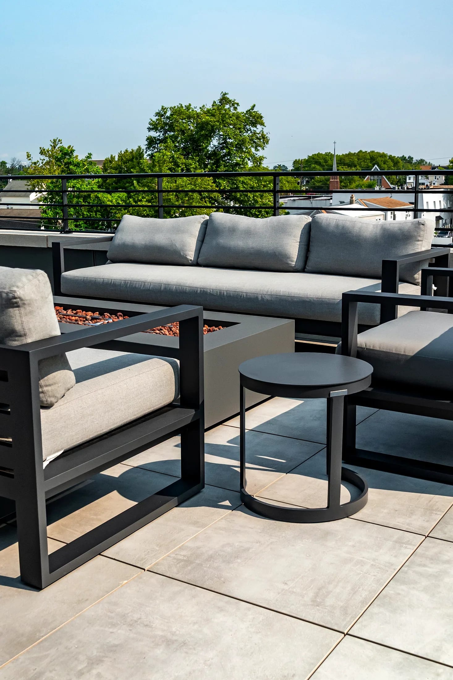 Sofa and firepit table on the terrace with trees beyond the railing